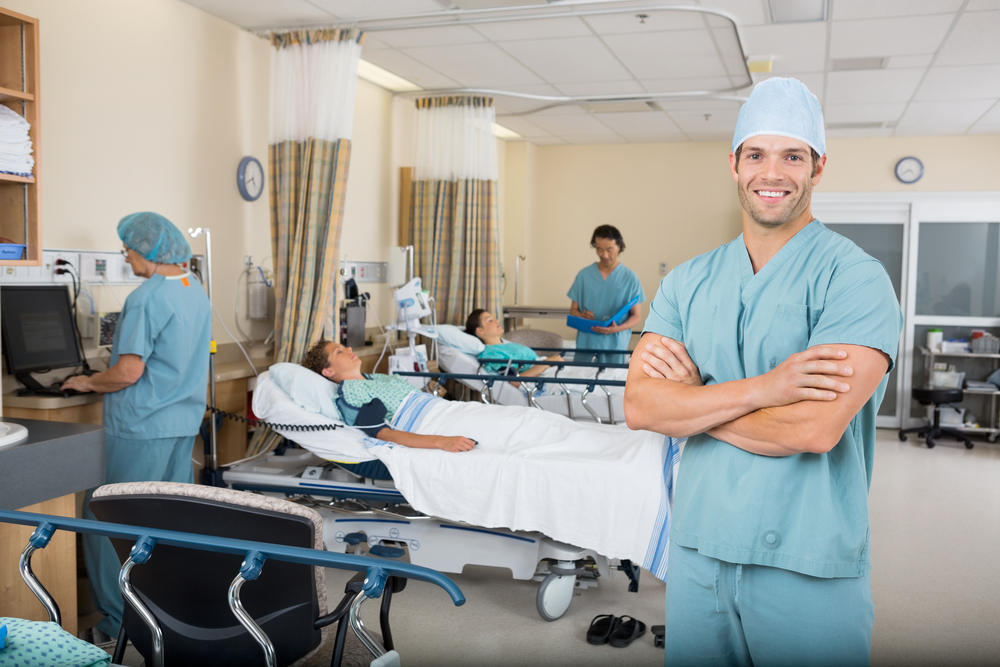 Portrait,Of,Confident,Male,Nurse,With,Colleagues,And,Patients,In