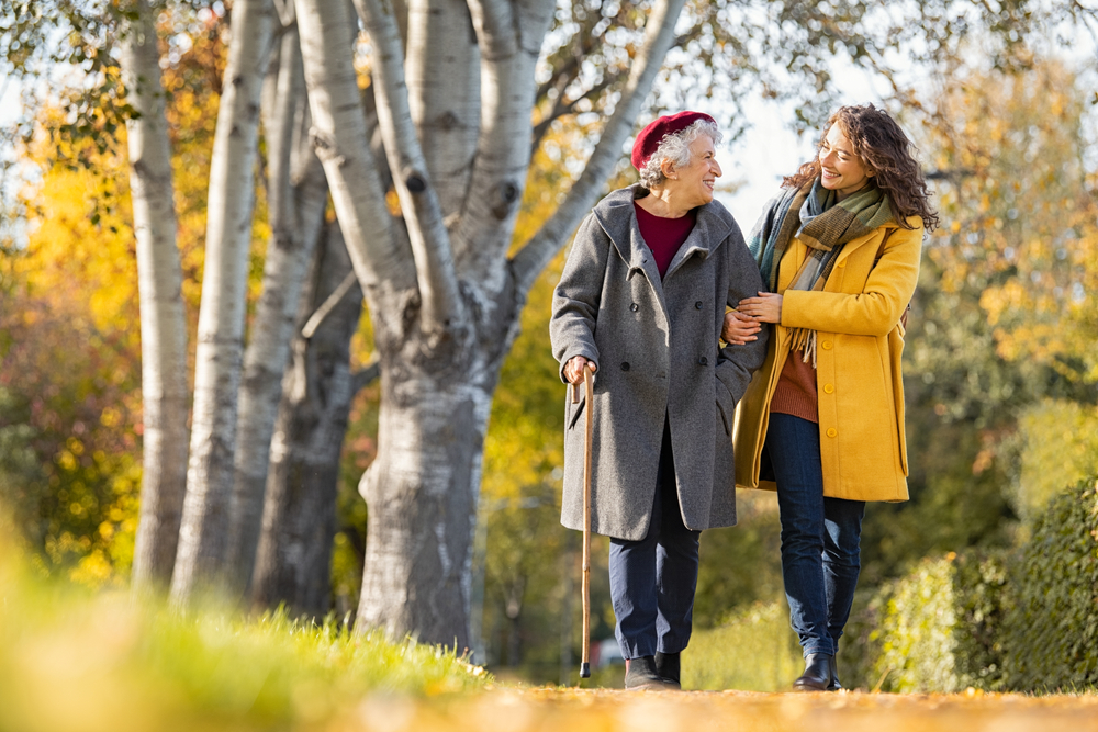 Granddaughter,Walking,With,Senior,Woman,In,Park,Wearing,Winter,Clothing.