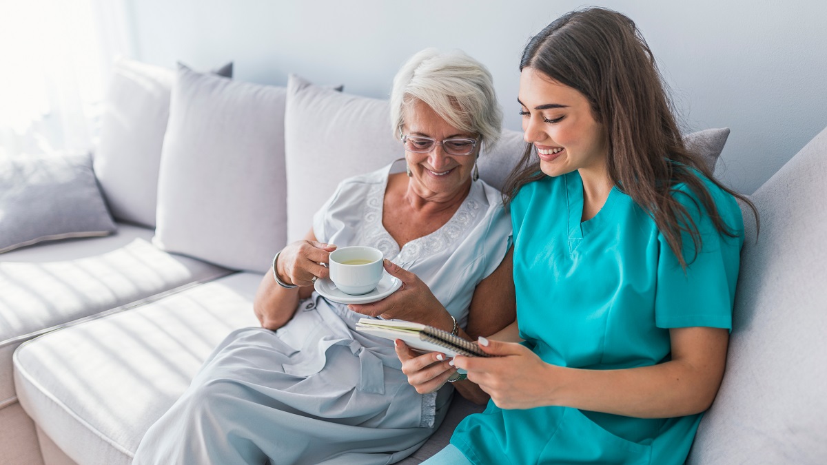 Woman,Reading,A,Book,While,Sitting,With,Happy,Grandmother,Drinking