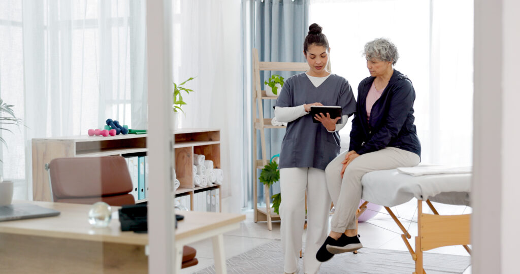 Female healthcare worker showing information on a tablet to a senior woman in a bright, modern home care setting.