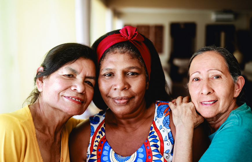 Happy multiracial senior women looking at camera at home.