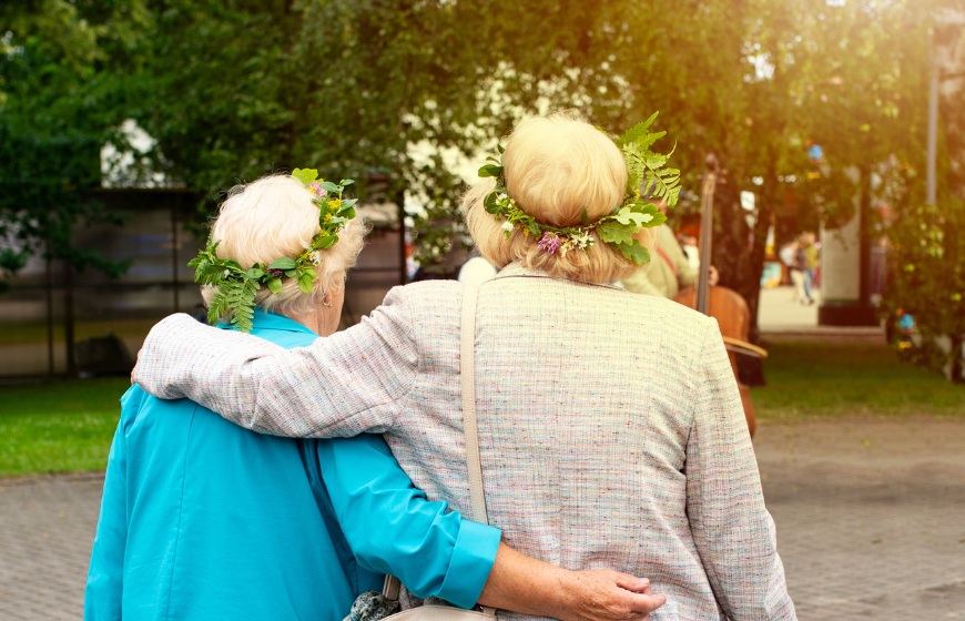 A happy couple of older women with midsummer garland enjoying their time appreciating leisure and freedom