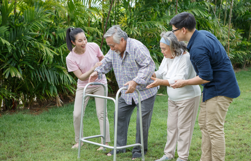 Senior Asian man trying walk with walker and his family as part of his hospital discharge plan and recovery