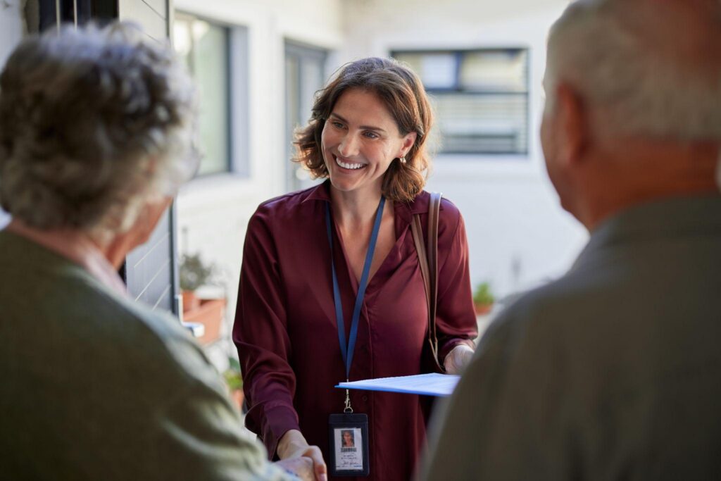 Caregiver with lanyard greeting and shaking hands with an elderly client